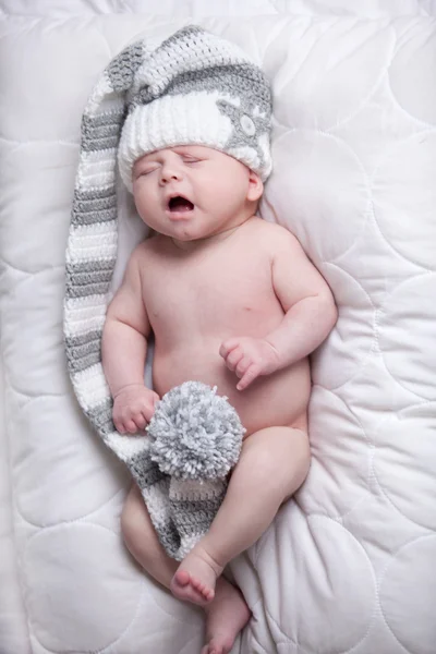 Baby with cap is yawning on a blanket — Stock Photo, Image