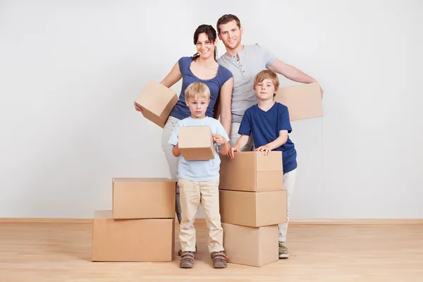 Happy young family carrying boxes — Stock Photo, Image