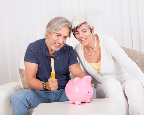 Senior couple raiding a piggybank — Stock Photo, Image