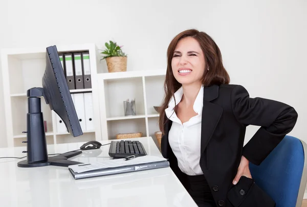 Empresaria teniendo dolor de espalda en el trabajo —  Fotos de Stock