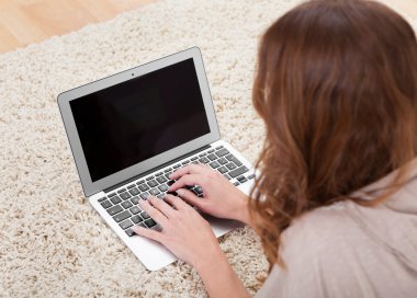 dizüstü bilgisayar kullanan halı üzerinde oturan kadın