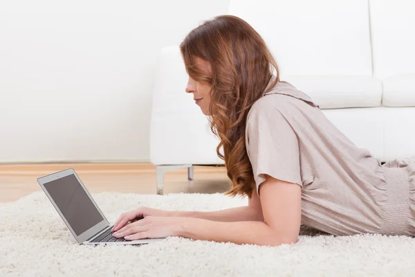 Dizüstü bilgisayar kullanan halı üzerinde oturan kadın — Stok fotoğraf