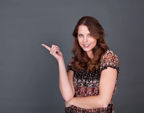 Mujer sonriente apuntando al copyspace —  Fotos de Stock