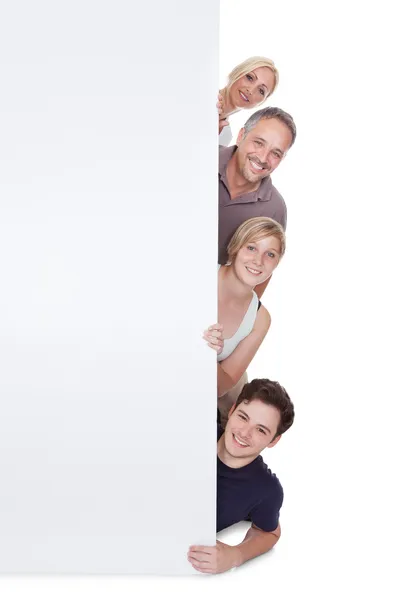 Família feliz segurando cartaz em branco — Fotografia de Stock
