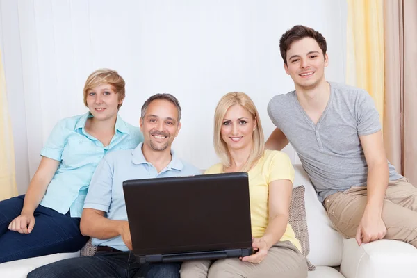 Семья вместе сидит на диване с ноутбуком — стоковое фото