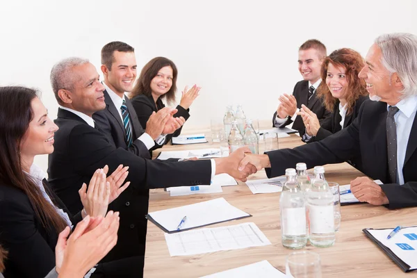 Equipe de negócios sentada na mesa e aplaudindo — Fotografia de Stock