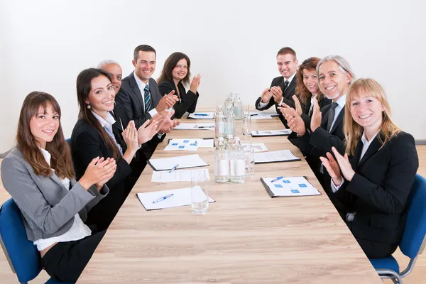 Equipe de negócios sentada na mesa e aplaudindo — Fotografia de Stock