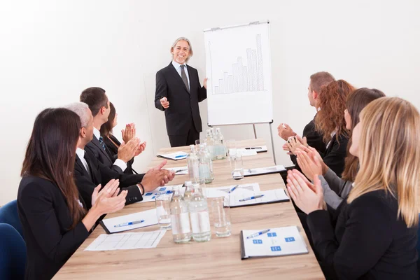 Equipo de negocios sentado en la mesa y aplaudiendo — Foto de Stock