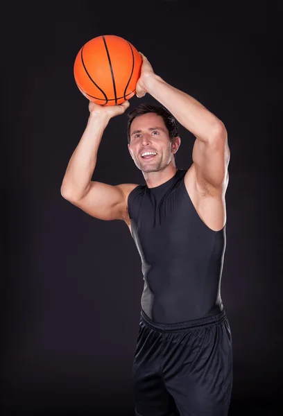 Молодой человек бросает баскетбол — стоковое фото