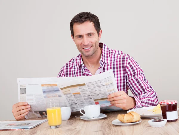 Ung man läsa tidningen på frukost — Stockfoto