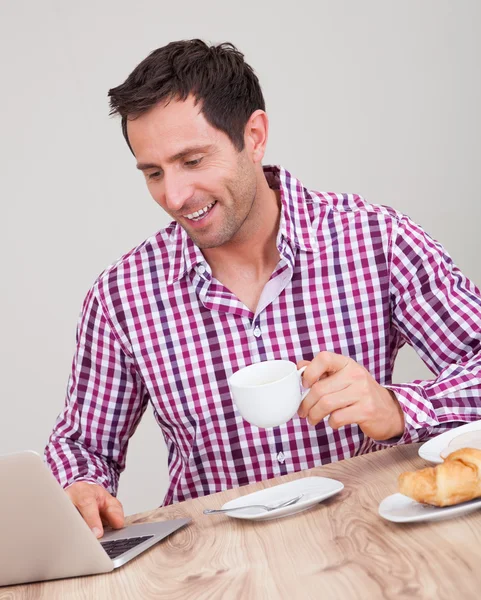 Portret van een jonge man met behulp van laptop bij het ontbijt — Stockfoto
