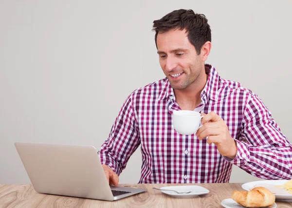 Retrato de hombre joven usando el ordenador portátil en el desayuno —  Fotos de Stock