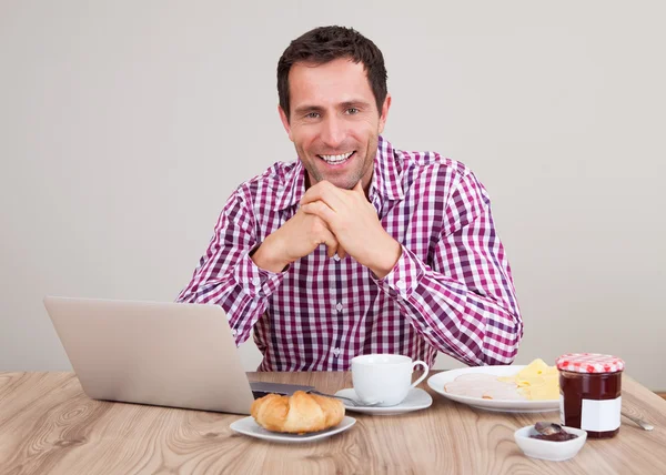 Ritratto di giovane uomo che utilizza il computer portatile a colazione — Foto Stock