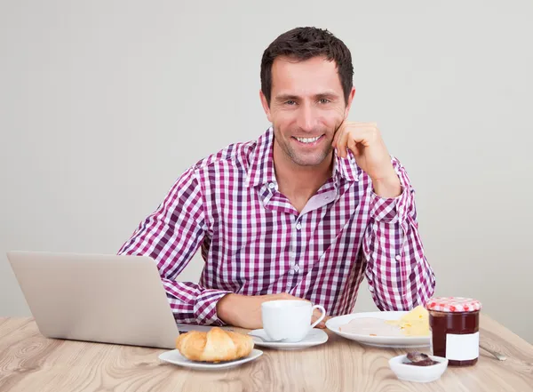 Ritratto di giovane uomo che utilizza il computer portatile a colazione — Foto Stock