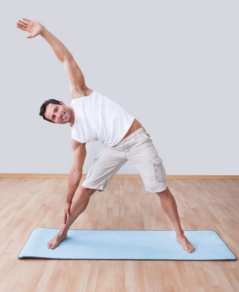 Junger Mann trainiert auf Gymnastikmatte — Stockfoto