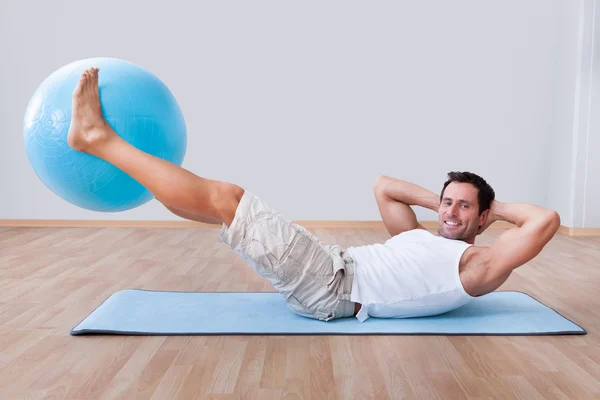 Jovem se exercitando em uma bola de pilates — Fotografia de Stock