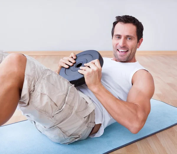 Молодой человек упражняется на коврик упражнения — стоковое фото