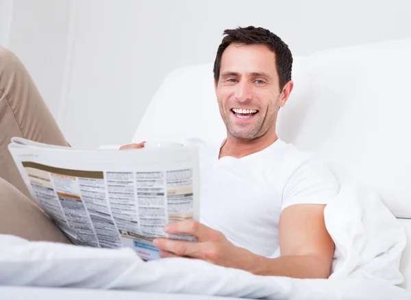 Joven sosteniendo la taza en la mano leyendo el periódico —  Fotos de Stock