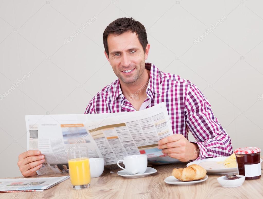 junger Mann lesen Zeitung beim Frühstück — Stockfoto © AndreyPopov