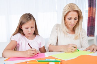 Anne ve kızı birlikte çiziyorlar.
