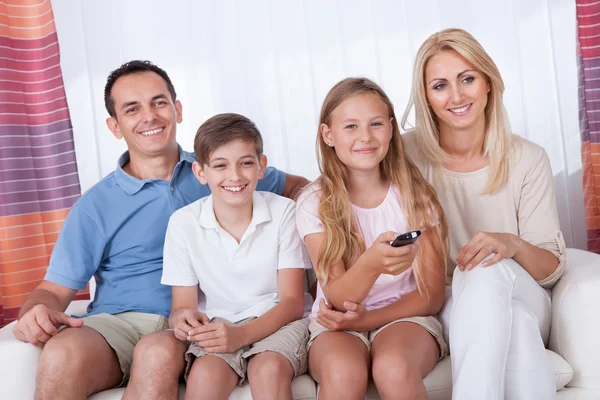 Familia feliz en un sofá viendo la televisión — Foto de Stock