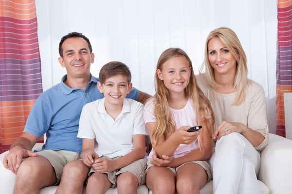 Šťastná rodina na pohovce se dívat na televizi — Stock fotografie