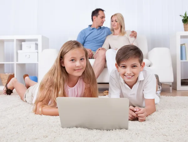 Niños en la alfombra usando tableta y computadora portátil — Foto de Stock