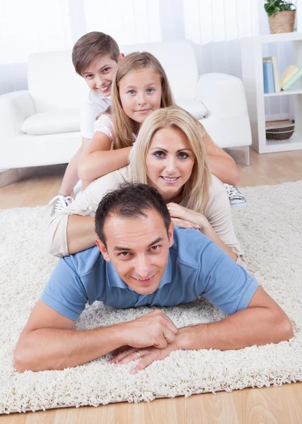 Familia feliz acostado en la alfombra en la sala de estar — Foto de Stock