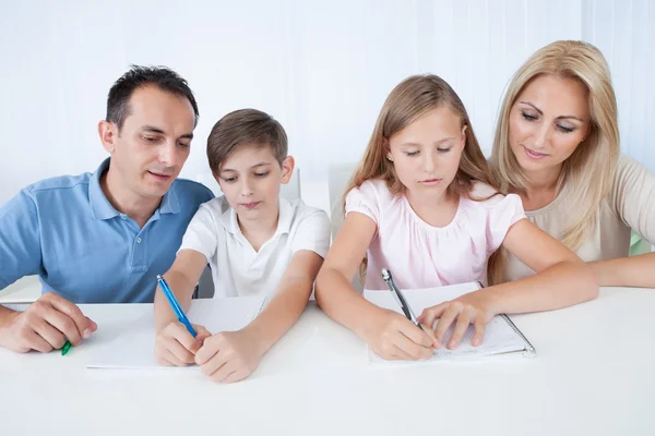 Pais ajudando seus filhos com seus trabalhos de casa — Fotografia de Stock