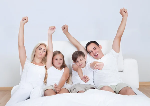 Yatağın üstüne oturan mutlu bir aile portresi — Stok fotoğraf