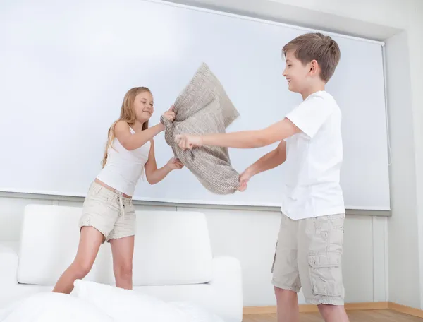 Geschwister liefern sich Kissenschlacht im Bett — Stockfoto