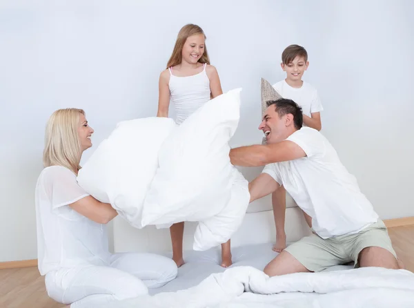 Family Having A Pillow Fight Together On Bed Stock Image