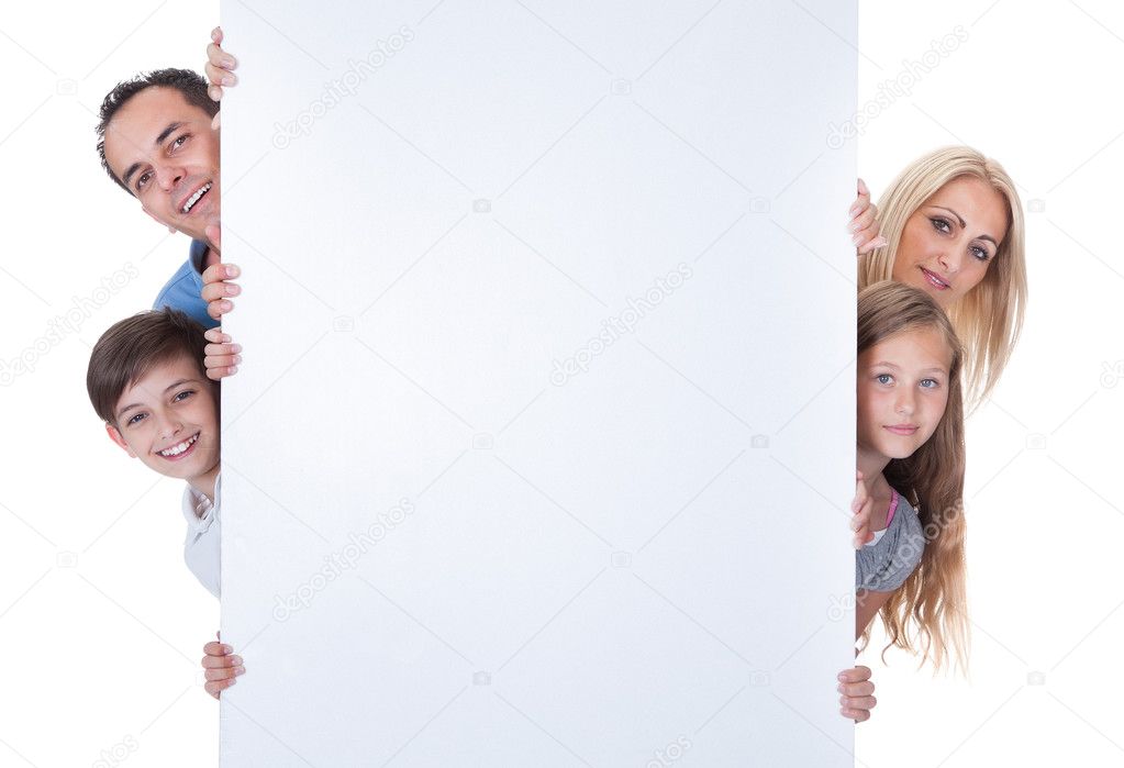 Portrait Of Family Peeping Behind Blank Board