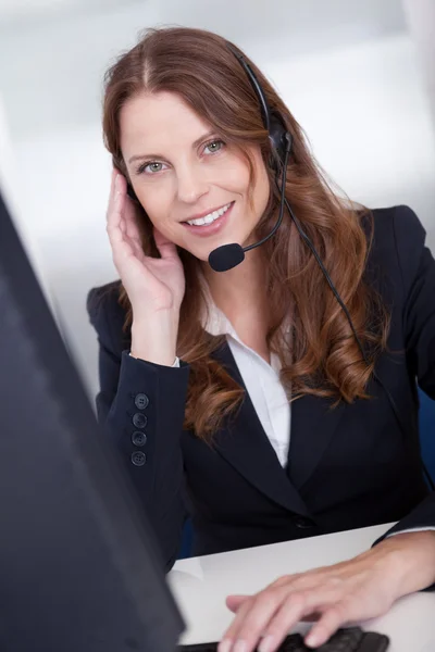 Smiling call center worker sitting typing — Stock Photo, Image