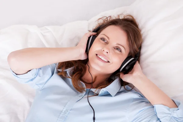 Femme relaxante écoutant de la musique au lit — Photo