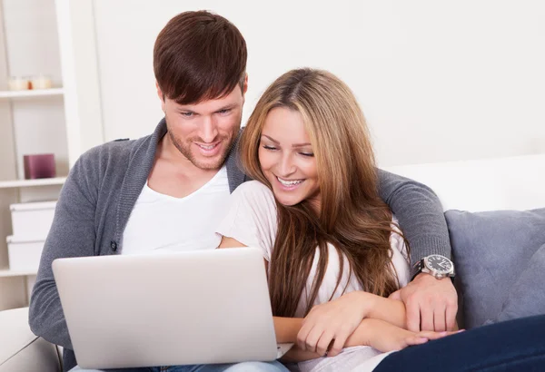 Happy young couple using computer at home — Stock Photo, Image