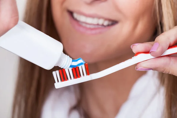 Mom put toothpaste on toothbrush — Stock Photo, Image