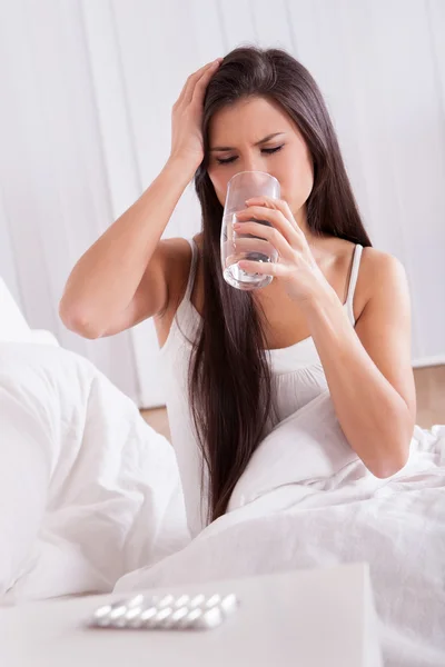 Nemocná žena v posteli užívat léky — Stock fotografie