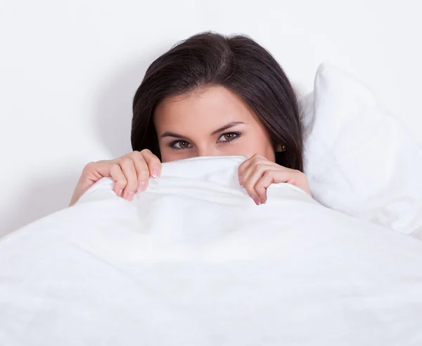 Pretty woman snuggling down in bed Stock Image