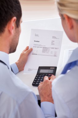 Colleagues checking an invoice on a calculator clipart
