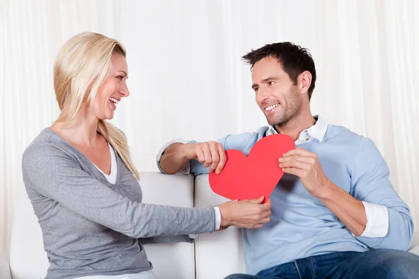 Casal romântico segurando um coração vermelho — Fotografia de Stock