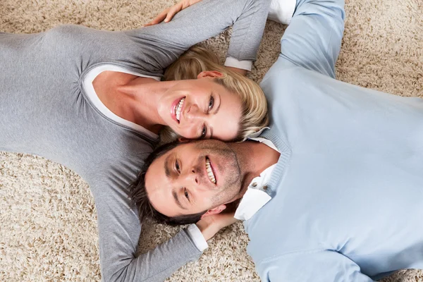 Homme et femme couchés tête contre tête sur le tapis — Photo