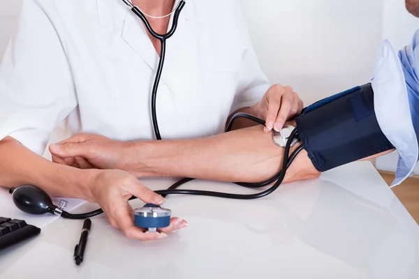 Médico que toma uma pressão arterial de pacientes — Fotografia de Stock