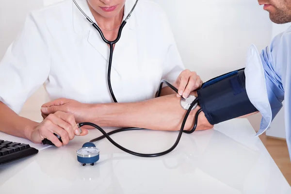 Médico que toma uma pressão arterial de pacientes — Fotografia de Stock