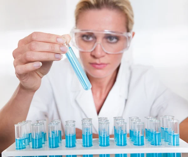 Lab technicus vrouw kijken naar testubes — Stockfoto