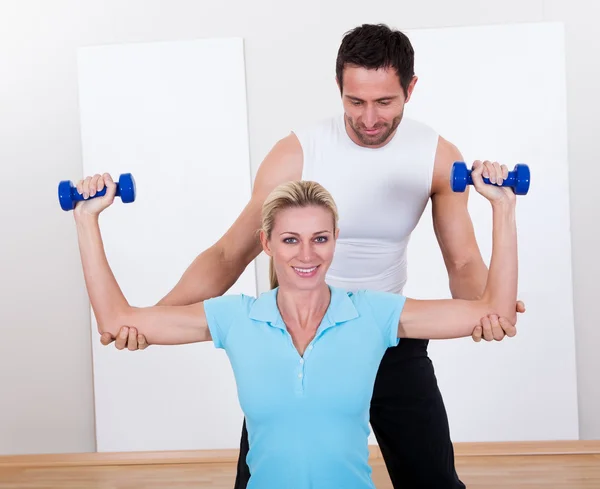 Fitness instructor helping a woman workout — Stock Photo, Image