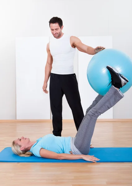 Instructor helping a woman with pilates exercises — Stock Photo, Image