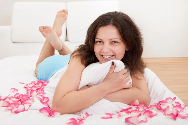 Mulher sorridente rodeada de pétalas de rosa — Fotografia de Stock