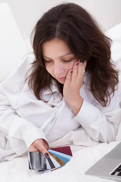 Mujer contemplando sus tarjetas de crédito — Foto de Stock