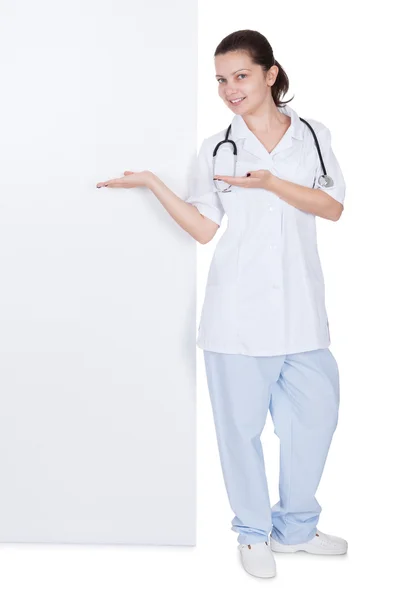 Sorridente giovane donna medico indicando a segno — Foto Stock